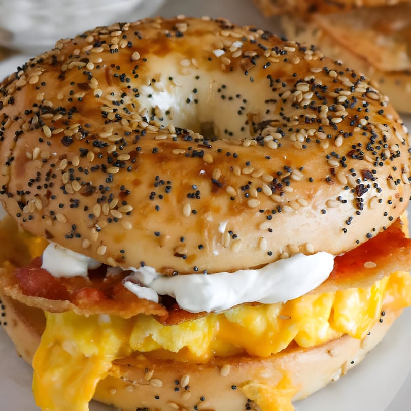 Close-up of an everything bagel sandwich with scrambled eggs, bacon, and cream cheese.